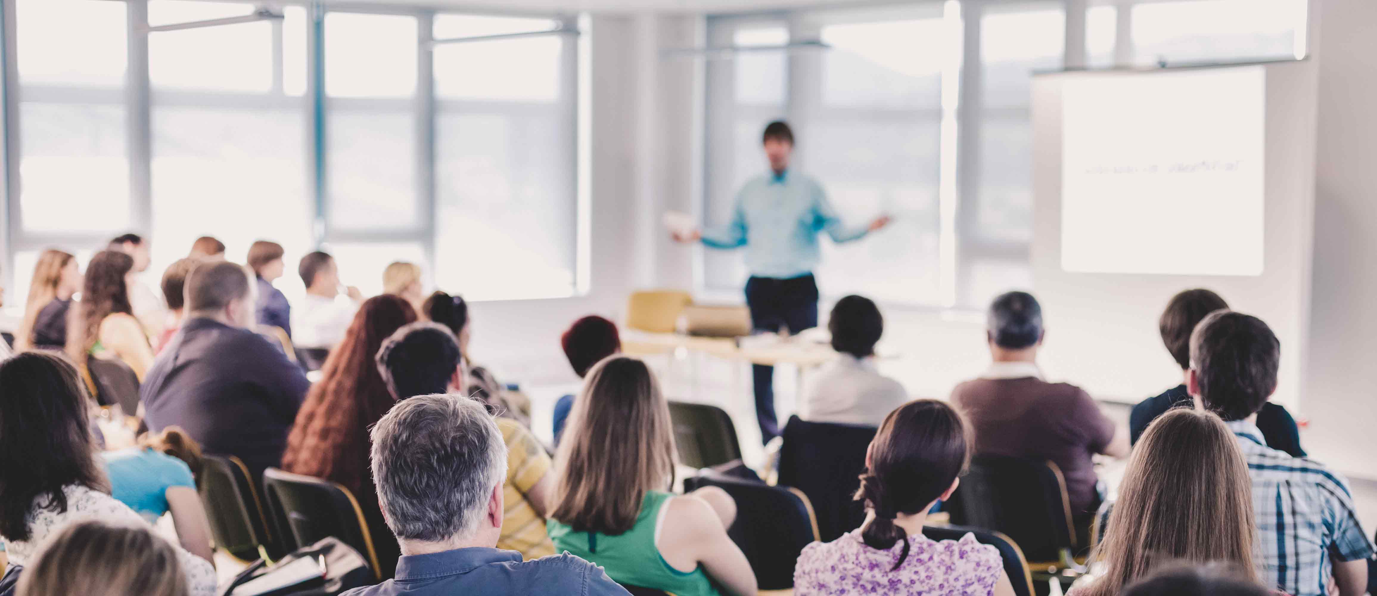 Speaker giving a presentation to a crowd of people sitting on chairs.