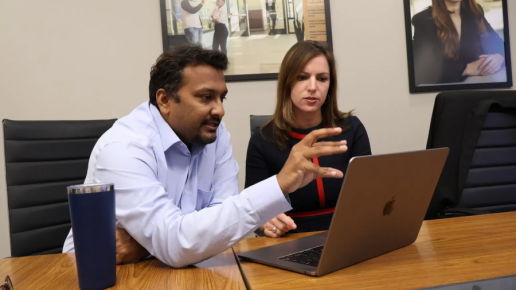 Two people reviewing information and discussing with a laptop in front of them.