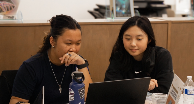 Two students were talking in front of the laptop