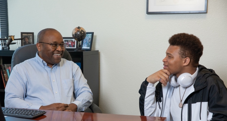 Dr. Peter Maribei is talking with a student in the Student Success Hub