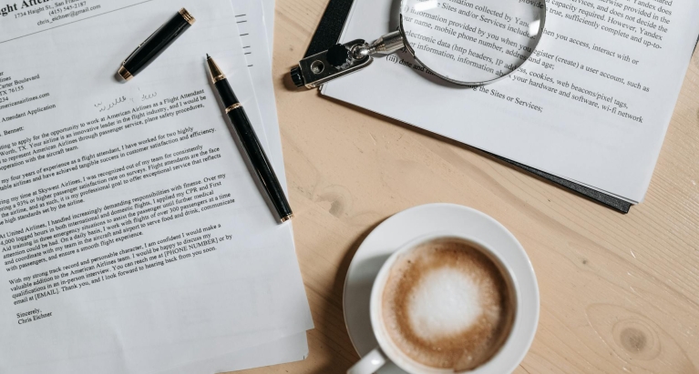 Coffee, Pen and Magnifying Glass on Papers