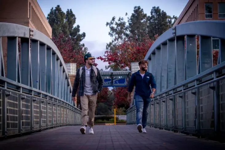 Irvine, CA - January 07: Narek Kajikian, left, a 3rd year aerospace engineer, and Musab Al Kindy, a 3rd year mechanical engineer, walk across a bridge amidst a mostly empty University of California-Irvine campus in Irvine Friday, Jan. 7, 2022. The University of California officials announced the extension of remote instruction on five campuses, stating the high coronavirus positivity rates call for extra precautions at UC campuses. (Allen J. Schaben / Los Angeles Times via Getty Images)Los Angeles Times via