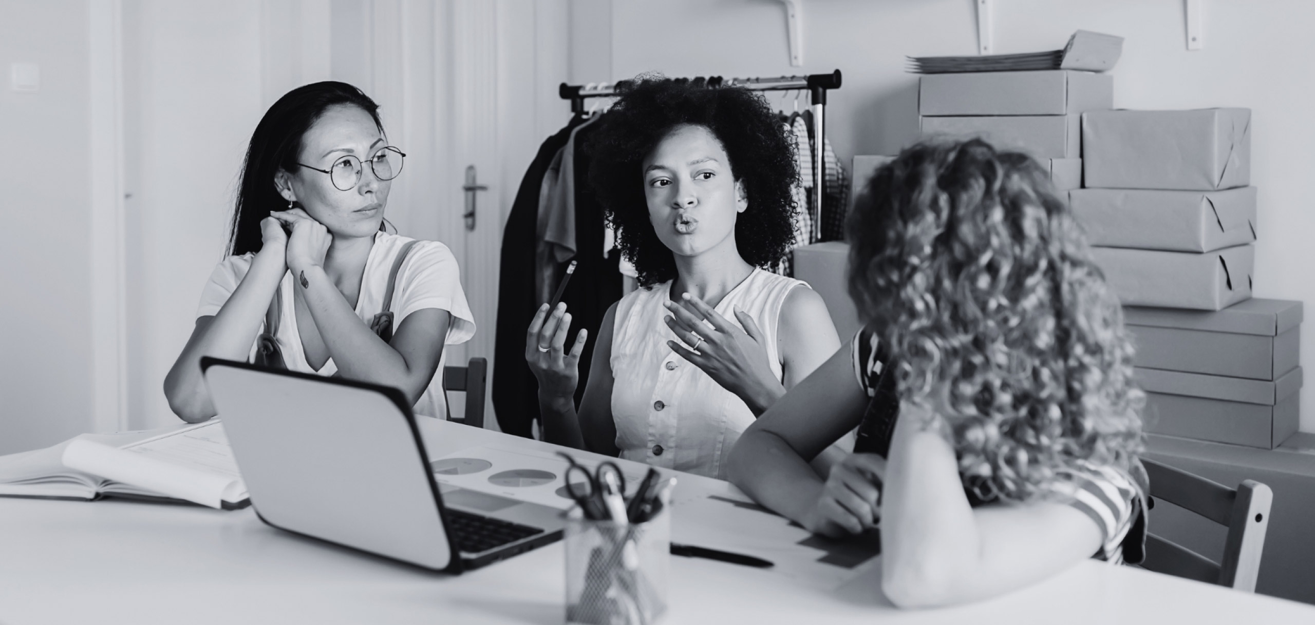 Black and white image of three females having a discussion at a table.