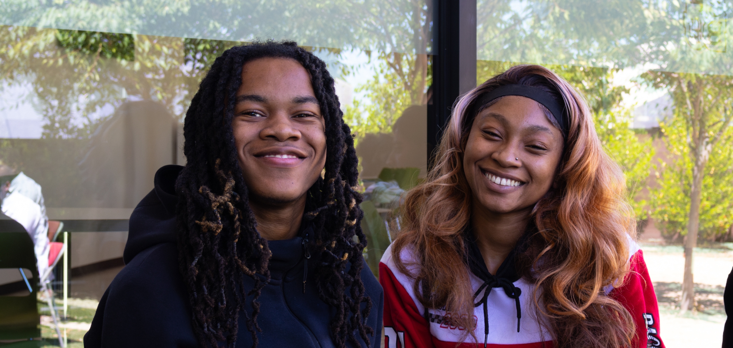 Two new female students are smiling to the camera. 