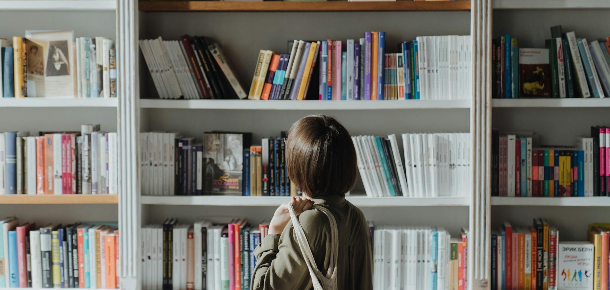 A woman browsing a bookshelf in a well-lit bookstore, exploring various titles.