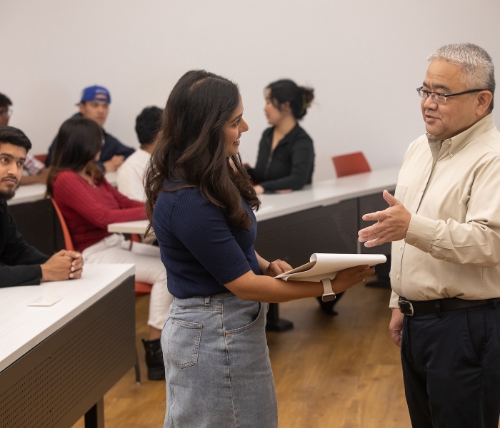 Dr.Iwagoshi is talking to a female student in the Lecture Hall with a group of students.