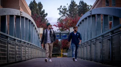 Irvine, CA - January 07: Narek Kajikian, left, a 3rd year aerospace engineer, and Musab Al Kindy, a 3rd year mechanical engineer, walk across a bridge amidst a mostly empty University of California-Irvine campus in Irvine Friday, Jan. 7, 2022. The University of California officials announced the extension of remote instruction on five campuses, stating the high coronavirus positivity rates call for extra precautions at UC campuses. (Allen J. Schaben / Los Angeles Times via Getty Images)Los Angeles Times via