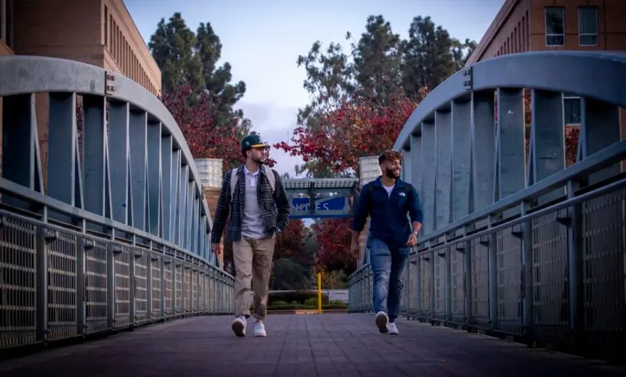 Irvine, CA - January 07: Narek Kajikian, left, a 3rd year aerospace engineer, and Musab Al Kindy, a 3rd year mechanical engineer, walk across a bridge amidst a mostly empty University of California-Irvine campus in Irvine Friday, Jan. 7, 2022. The University of California officials announced the extension of remote instruction on five campuses, stating the high coronavirus positivity rates call for extra precautions at UC campuses. (Allen J. Schaben / Los Angeles Times via Getty Images)Los Angeles Times via