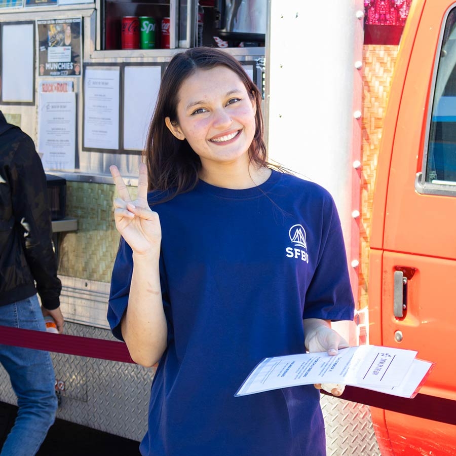 Female student smiling and holding up the peace sign.