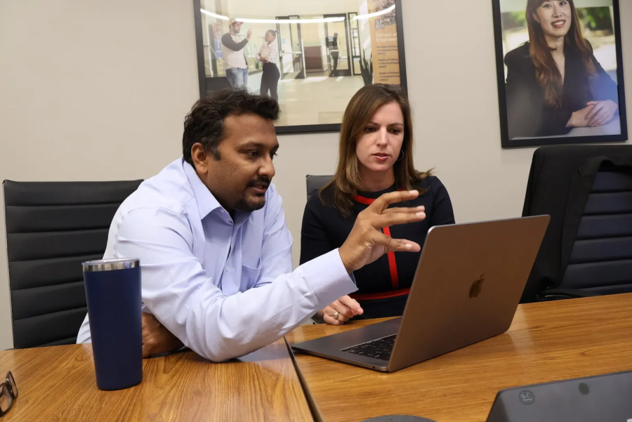 Two people reviewing information and discussing with a laptop in front of them.